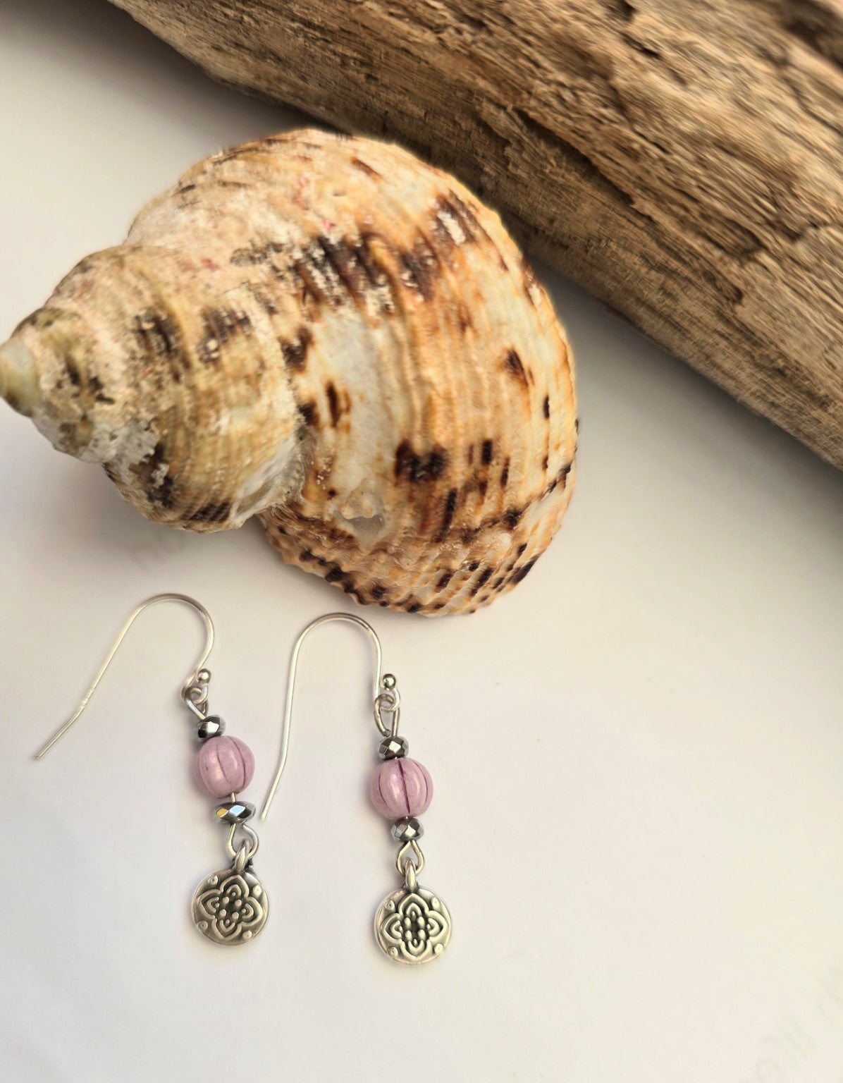 Flower earrings beside a seashell